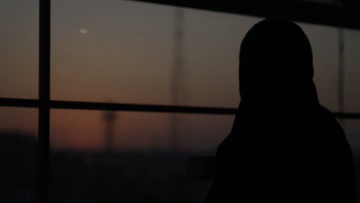 جلسة هادئة مطلة على الميناء البحري وقت غروب الشمس ، تعديل المزاج بشرب الكافيين, الاستمتاع باحتساء المشروب المفضل، سيدة عربية خليجية سعودية ترتدي العباءة تمسك بيدها كوب من القهوة