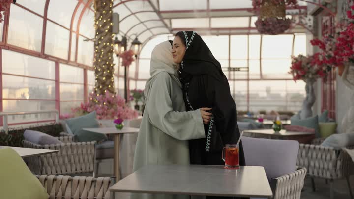 تعابير السعادة والسرور بلمة الرفاق، شرب المشروبات البارده ، مطاعم وكافيهات فى المملكة العربية السعودية ، امراه عربية خليجية سعودية تجلس فى مطعم وتمسك بيها كوب من العصير