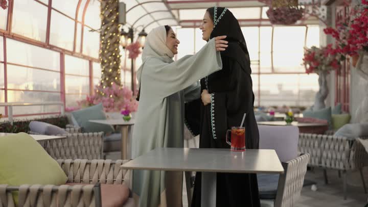 تعابير السعادة والسرور بلمة الرفاق، شرب المشروبات البارده ، مطاعم وكافيهات فى المملكة العربية السعودية ، امراه عربية خليجية سعودية تجلس فى مطعم وتمسك بيها كوب من العصير