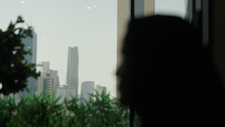 تصوير ظلي لرجل عربي خليجي سعودي ينظر من خلال النافذه الى أبراج الملك عبد الله الماليه في مدينة الرياض , الاعجاب بالمركز المالي التجاري , النمو والتقدم العمراني في البلاد , رؤية 2030