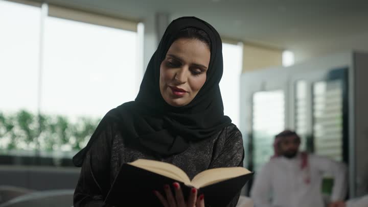 ممارسة هواية المطالعة, مفهوم الشغف بالقراءة, امراة عربية خليجية سعودية  ترتدي العباءة والحجاب  تقوم بقراءه كتاب داخل مقر الشركة, كتب وروايات هادفه ومسليه ، التعلم والتثقيف من خلال قراءه الكتب الهادفه