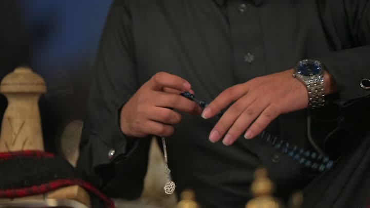 Folk traditions and heritage inside a tent of the House of Poetry in the desert of the Kingdom of Saudi Arabia, the calm atmosphere in camping areas, traditional Arab gatherings in the wilderness, Saudi customs and traditions, a traditional folk outing in the desert, a close-up shot of a Saudi Gulf Arab man holding a prayer bead in his hand.