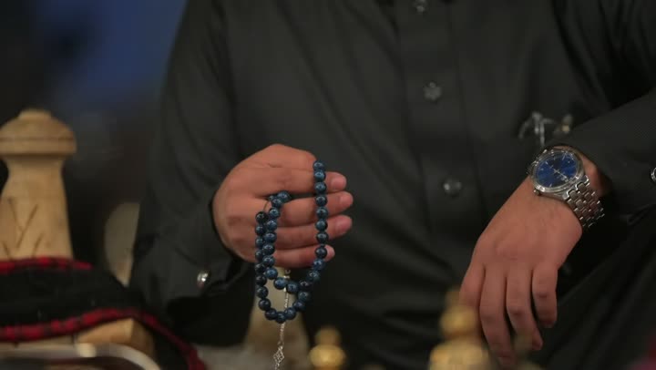 شعبيات وتراثيات داخل خيمة بيت الشعر في صحراء المملكة العربية السعودية، الأجواء الهادئة في اماكن التخييم، مجالس عربيه تراثيه في البراري, عادات وتقاليد سعودية، كشتة بر شعبية تقليدية في البادية، تصوير مقرب لرجل عربي خليجي سعودي يمسك بيده سبحة