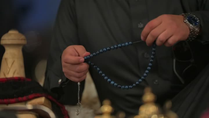 شعبيات وتراثيات داخل خيمة بيت الشعر في صحراء المملكة العربية السعودية، الأجواء الهادئة في اماكن التخييم، مجالس عربيه تراثيه في البراري, عادات وتقاليد سعودية، كشتة بر شعبية تقليدية في البادية، تصوير مقرب لرجل عربي خليجي سعودي يمسك بيده سبحة