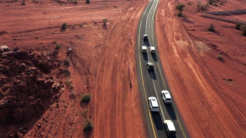 Desert landscapes in Saudi Arabia, dunes and soft golden sands in the vast Arabian Desert, aerial drone footage of a 4x4 Jeep in the middle of an asphalt road