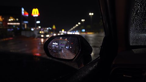 Rainy winter weather, car traffic on the roads of Riyadh, Saudi Arabia at night, raindrops falling on car windows, roads, streets and landmarks of Riyadh