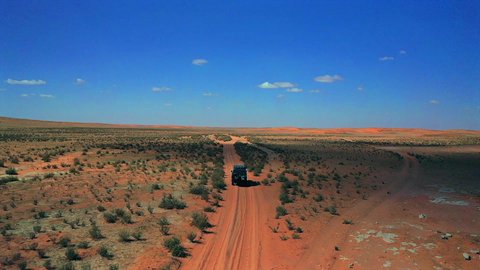 Wandering through the vast Arabian desert, an aerial drone shot of an old Jeep SUV amidst the sand and desert, the desert landscape of Saudi Arabia.