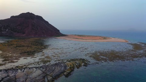 Tourist attractions in the Kingdom of Saudi Arabia, aerial drone photography of Jabal Kadmbel Island in Asir, calm sea waves on the Red Sea coast, mountain peaks and heights during the day