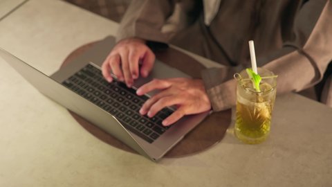 مفهوم ادخال البيانات، النقر على لوحة المفاتيح، صناعة المحتويات النصية، تصوير مقرب ليد رجل عربي خليجي اماراتي يستخدم  الحاسوب المحمول، الكتابة على جهازاللابتوب، دمج التكنولوجيا الحديثة بالحياة العملية، الاستمتاع بتناول المشروبات