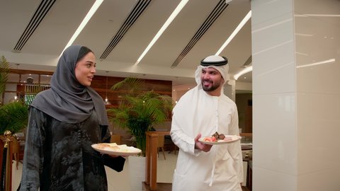 قضاء وقت ممتع في الخارج، ,زوجان عربيان خليجيان اماراتيان يرتديان الزي التقليدي يقومان بتناول وجبه الغذاء في احدى المطاعم الاماراتية، ايماءات السعادة و السرور