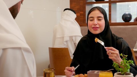 قضاء وقت ممتعه خارج المنزل في عطلة نهاية الاسبوع، طاولة مليئة باطباق متنوعه ومختلفه من المأكولات الشهية، مطعم راقي في الامارات العربية المتحدة، المحبة والمودة بين الزوجين, زوجان عربيان اماراتيان يقوم بتناول الطعام في المطعم, مفهوم الاسره السعيده