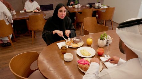 مطعم راقي في الامارات العربية المتحدة، المحبة والمودة بين الزوجين، طاولة مليئة باطباق متنوعه ومختلفه من المأكولات الشهية، قضاء وقت ممتعه خارج المنزل في عطلة نهاية الاسبوع, زوجان عربيان اماراتيان يقوم بتناول الطعام في المطعم, مفهوم الاسره السعيده