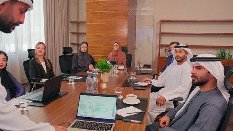 التفاني والاحترافية في الانجاز، شرح العمليات والصفقات التجارية، التفاهم والتعاون بين الزملاء لتحقيق أهداف الشركة, نقاشات خاصة بالعمل, استخدام الحاسوب المحمول، اجتماع عمل مع موظفين عرب خليجيين اماراتيين مع رجال أعمال أجانب في غرفة الاجتماعات، ضمان فهم واضح للأعمال