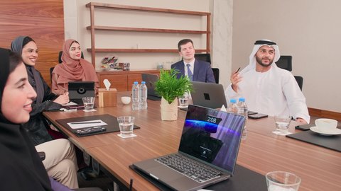 التفاني والاحترافية في الانجاز، شرح العمليات والصفقات التجارية، التفاهم والتعاون بين الزملاء لتحقيق أهداف الشركة, نقاشات خاصة بالعمل, استخدام الحاسوب المحمول، اجتماع عمل مع موظفين عرب خليجيين اماراتيين مع رجال أعمال أجانب في غرفة الاجتماعات، ضمان فهم واضح للأعمال