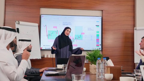 بيئة العمل المريحة في الشركات الاماراتية, إنجاز المهام عبر جهاز الحاسوب، عرض البيانات الاحصائية على الشاشة، الاتفاق على المشاريع التجارية، اجتماع عمل بين موظفين عرب خليجيين اماراتيين مع رجال أعمال أجانب في غرفة الاجتماعات، استخدام الأجهزة التقنية الحديثة في المكاتب