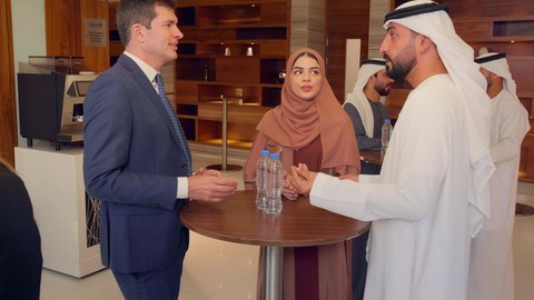 عقد صفقات عمل جديدة، الاتفاق على المشاريع التجارية، اجتماع فريق عمل عرب خليجيين اماراتيين مع وفد اجنبي في قاعة مؤتمرات فخمة، المناقشة وتبادل الافكار بين رجال الأعمال، معرض أعمال في الامارات العربية المتحدة مع المندوبين