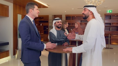 عقد صفقات عمل جديدة، الاتفاق على المشاريع التجارية، اجتماع فريق عمل عرب خليجيين اماراتيين مع وفد اجنبي في قاعة مؤتمرات فخمة، المناقشة وتبادل الافكار بين رجال الأعمال، معرض أعمال في الامارات العربية المتحدة مع المندوبين