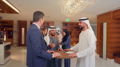 عقد صفقات عمل جديدة، الاتفاق على المشاريع التجارية، اجتماع فريق عمل عرب خليجيين اماراتيين مع وفد اجنبي في قاعة مؤتمرات فخمة، المناقشة وتبادل الافكار بين رجال الأعمال، معرض أعمال في الامارات العربية المتحدة مع المندوبين