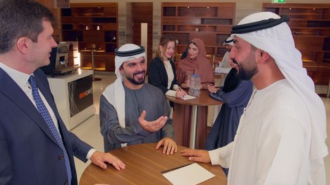 Agreement on business projects, a meeting of a team of Arab Gulf Emiratis with a foreign delegation in a luxurious conference hall, discussion and exchange of ideas among businessmen, a business exhibition in the United Arab Emirates with representatives, concluding new business deals.