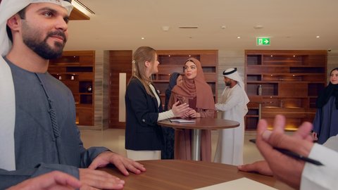 الاتفاق على المشاريع التجارية، اجتماع فريق عمل عرب خليجيين اماراتيين مع وفد اجنبي في قاعة مؤتمرات فخمة، المناقشة وتبادل الافكار بين رجال الأعمال، معرض أعمال في الامارات العربية المتحدة مع المندوبين، عقد صفقات عمل جديدة