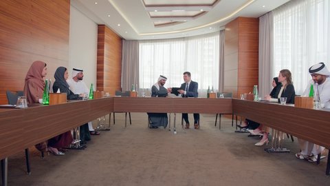 اجتماع فريق عمل عرب خليجيين اماراتيين مع وفد اجنبي في قاعة مؤتمرات فخمة، المناقشة وتبادل الافكار بين رجال الأعمال، إلقاء الخطابات في صالات المؤتمرات، معرض أعمال في الامارات العربية المتحدة مع المندوبين، عقد صفقات عمل جديدة