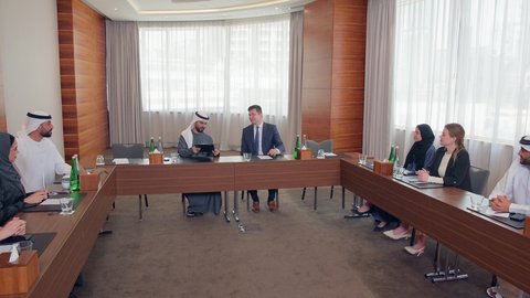 اجتماع فريق عمل عرب خليجيين اماراتيين مع وفد اجنبي في قاعة مؤتمرات فخمة، المناقشة وتبادل الافكار بين رجال الأعمال، إلقاء الخطابات في صالات المؤتمرات، معرض أعمال في الامارات العربية المتحدة مع المندوبين، عقد صفقات عمل جديدة