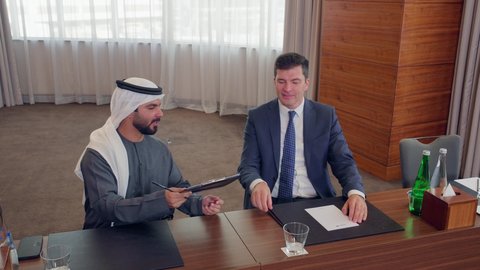 المناقشة وتبادل الافكار بين رجال الأعمال، عقد صفقات عمل جديدة، الاتفاق على المشاريع التجارية، اجتماع فريق عمل عرب خليجيين اماراتيين مع وفد اجنبي في قاعة مؤتمرات فخمة، معرض أعمال في الامارات العربية المتحدة مع المندوبين