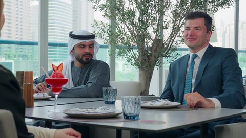 عرض أفكار ومشاريع جديد،  بناء علاقات اجتماعية ناجحة, المذاق الطيب للمأكولات والمشروبات، اجتماع عمل في مكان خارج مقر الشركة, مشاركة الأوقات الممتعة, تصوير مقرب لمجموعة من الأصدقاء الاجانب والعرب خليجيين إماراتيين يجلسون على طاولة في إحدى المطاعم في الإمارات