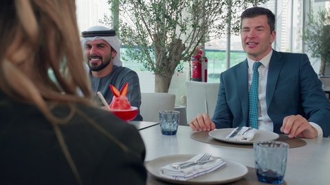 تبادل الثقافات والمعلومات المختلفة، بناء علاقات اجتماعية, المذاق الطيب للمأكولات والمشروبات، اجتماع عمل في مكان خارج مقر الشركة, مشاركة الأوقات الممتعة, تصوير مقرب لمجموعة من الأصدقاء الاجانب والعرب خليجيين إماراتيين يجلسون على طاولة في إحدى المطاعم في الإمارات