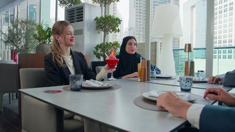 اشارات التوافق والاتفاق، بناء علاقات اجتماعية, المذاق الطيب للمأكولات والمشروبات، اجتماع عمل في مكان خارج مقر الشركة, مشاركة الأوقات الممتعة, تصوير مقرب لمجموعة من الأصدقاء الاجانب والعرب خليجيين إماراتيين يجلسون على طاولة في إحدى المطاعم في الإمارات