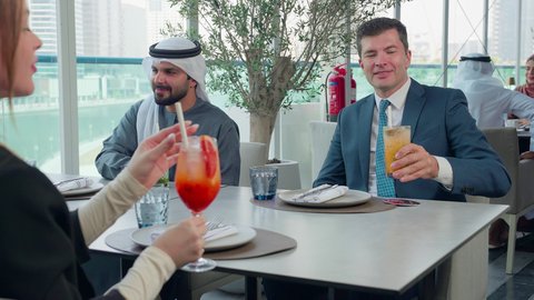 شرب المشروبات الباردة, مشاركة الأوقات الممتعة, المناقشة وتبادل الأحاديث، اجتماع عمل في مكان خارج مقر الشركة, بناء علاقات اجتماعية ناجحة, مجموعة من الأصدقاء الاجانب والعرب خليجيين إماراتيين يجلسون على طاولة في إحدى المطاعم في الإمارات