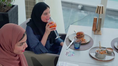 تناول وجبة خفيفة, بناء وتعزيز العلاقات والصداقات، مناقشة الاعمال وتبادل الافكار، إيماءات السعادة والسرور، اجتماع عمل في مكان خارج مقر الشركة, تصوير مقرب لصديقتان عربيتان خليجيتان اماراتيتان يجلسون على طاولة في إحدى المطاعم في الإمارات قضاء اوقات ممتعة مع الأصدقاء