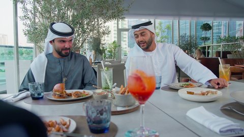 بناء وتعزيز العلاقات والصداقات، مناقشة الاعمال وتبادل الافكار، إيماءات السعادة والسرور، اجتماع عمل في مكان خارج مقر الشركة, مشاركة الأوقات الممتعة, تصوير مقرب لمجموعة من الأصدقاء العربيين الخليجيين الإماراتيين يجلسون على طاولة في إحدى المطاعم في الإمارات