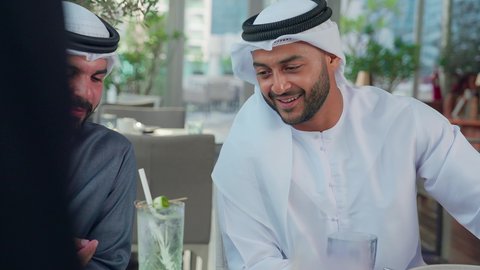 مناقشة الاعمال وتبادل الافكار، إيماءات السعادة والسرور، بناء وتعزيز العلاقات والصداقات، اجتماع عمل في مكان خارج مقر الشركة, مشاركة الأوقات الممتعة, تصوير مقرب لمجموعة من الأصدقاء العربيين الخليجيين الإماراتيين يجلسون على طاولة في إحدى المطاعم في الإمارات