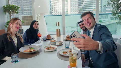 توثيق اللحظات المهمة، الاستمتاع بتناول الغداء في المطعم, مشاركة الأصدقاء الأوقات الممتعة, بناء علاقات اجتماعية ناجحة, تبادل الأحاديث والاخبار, مجموعة من الأصدقاء الاجانب والعرب خليجيين إماراتيين يجلسون على المائدة في إحدى المطاعم في الإمارات بإيماءات السرور