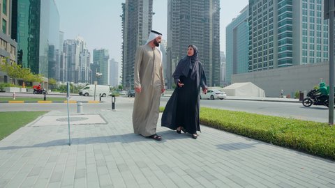 مشاهدة التطور العمراني في المدينة، تحديد موقع معين ، التجول واستنشاق الهواء النقي في الخارج, الفخر والاعتزاز بالتقدم المعماري ، النمو العمراني في الامارات ،زوجان عربيان خليجيان اماراتيان يرتديان الزي الاماراتي يشيران الي شئ ما