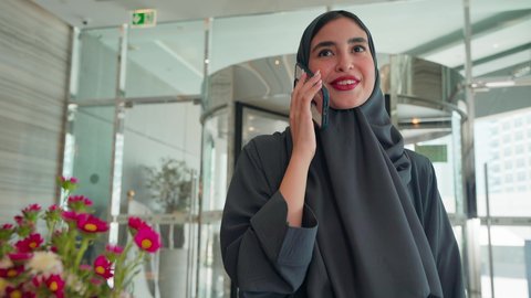 امراه عربيه خليجيه اماراتيه ترتدي العباءه والحجاب تتجول فى المول، اجراء مكالمه هاتفيه ، استخدام الهاتف المحمول ، الاستمتاع بالشراء والتبضع، إقتناء المستلزمات من المولات