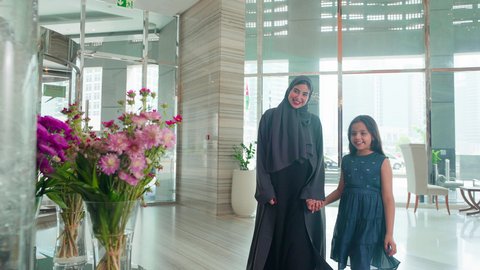 قضاء أوقات عائلية ممتعة،مشاعر الأمومة  والاهتمام، إقتناء المستلزمات من المولات، امراه عربية خليجية اماراتيه تضع وردة على شعر ابنتها بتعابير الحب, مفهوم الأسرة السعيدة ، الإستفادة من العروض والحسومات والتخفيضات الموسمية