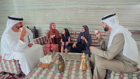 مفهوم الضيافة والاستقبال ,ايماءات البشاشة والترحيب بالضيوف ،  الاستمتاع بالمشروبات الساخنه ، كافيهات ومقاهي الامارات ،مجموعة اصدقاء عرب خليجيون اماراتيون يجلسون فى مقهي يتبادلون الاحاديث، قضاء اوقات سعيده مع العائلة