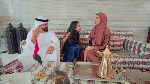 The concept of hospitality and reception, an Arab Gulf Emirati family sitting in a cafe exchanging conversations, spending happy times with the family, cheerful gestures and welcoming guests, enjoying hot drinks, cafes and coffee shops in the Emirates
