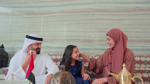 عائله عربيه خليجيه اماراتيه تجلس فى مقهي يتبادلون الاحاديث، قضاء اوقات سعيده مع الاسره، مفهوم الضيافة والاستقبال ,ايماءات البشاشة والترحيب بالضيوف ، الاستمتاع بالمشروبات الساخنه ، كافيهات ومقاهي الامارات