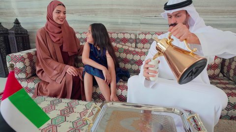 صب القهوه من الدله النحاسية ، المودة والالفة بين افراد الاسره ،ايماءات السرور والسعاده ، قضاء اوقات سعيده مع الاسره، كافيهات ومقاهي الامارات، عائله عربيه خليجيه اماراتيه تجلس فى مقهي