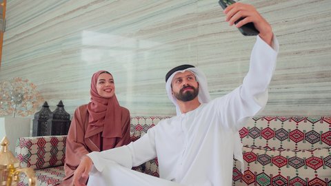 توثيق اللحظات التذكارية عبر الجوال ، التقاط صور السيلفي ،زوجان عربيان خليجيان اماراتيان  يجلسان فى المقهي،ايماءات السرور والسعاده ، كافيهات ومقاهي بالامارات، قضاء اوقات سعيده