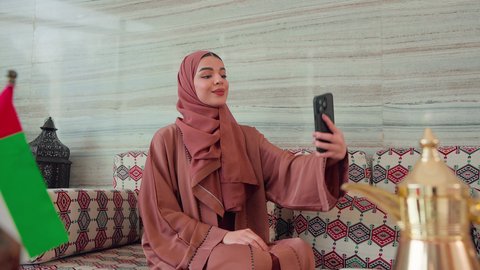 نزهه فى الخارج ، الاطمئنان على الاهل والاصدقاء،  اجراء مكالمه هاتفيه باستخدام الجوال ،ايماءات السرور والسعاده ، قضاء اوقات سعيده  ، كافيهات ومقاهي الامارات، توثيق اللحظات التذكاريه ، امراه عربيه خليجيه اماراتيه تجلس فى مقهي وبجانبها علم الامارات