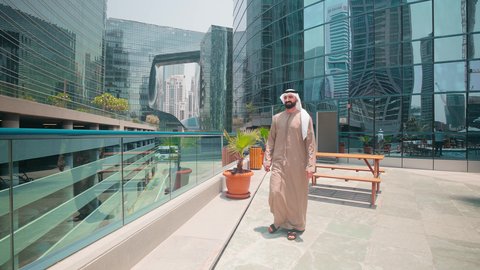 استخدام التقنيات الحديثة ،اجراء مكالمة هاتفية ، رجل عربي خليجي اماراتي يرتدي الكندورة والغتره يتجول حول المسبح في أحد الفنادق في المملكة العربية السعودية يستخدم الهاتف المحمول ،شاليهات و منتجعات فاخرة ، القيام بالأنشطة الترفيهية المسلية, استنشاق الهواء النقي