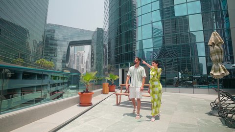 Pride and admiration for architectural progress, watching the urban development in the city, walking around and breathing fresh air outside, urban growth in the Emirates, determining a specific location, an Arab Gulf Emirati couple wearing casual clothes looking at something