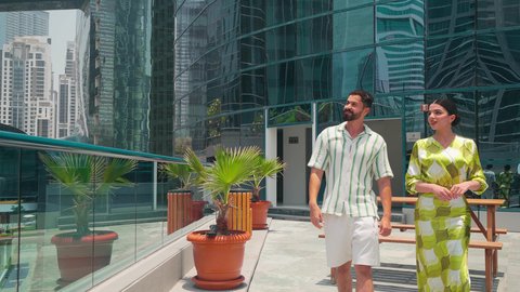 تحديد موقع معين ، مشاهدة التطور العمراني في المدينة، التجول واستنشاق الهواء النقي في الخارج,  الفخر والاعتزاز بالتقدم المعماري ، الاطمئنان على الاهل والاصدقاء ،النمو العمراني في الامارات ،زوجان عربيان خليجيان اماراتيان يرتديان الزي الكاجوال ينظران الي شئ ما