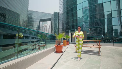 الفخر والاعتزاز بالتقدم المعماري ، الاطمئنان على الاهل والاصدقاء ، مشاهدة التطور العمراني في المدينة، التجول واستنشاق الهواء النقي في الخارج, النمو العمراني في الامارات ،امراه عربيه خليجيه اماراتيه ترتدي الزي الكاجوال تستخدم الهاتف المحمول