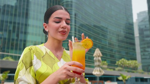 الاستمتاع بالمشروبات الصيفية المنعشة ، شاليهات و منتجعات فاخرة،  القيام بالأنشطة الترفيهية المسلية,امراه عربيه خليجيه اماراتيه ترتدي الزي الكاجوال تستمتع بالجلوس على طاولة حول المسبح في أحد الفنادق في المملكة العربية السعودية ، قضاء اوقات سعيدة