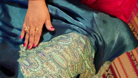 تقديم الهدايا في المناسبات السعيدة، العادات الإماراتية في تجهيز هدايا العروس، تصوير مقرب ليد ام العريس تحمل جلابية مطرزة  لتقديمها ضمن مراسم الزواج، الزي الشعبي التراثي التقليدي